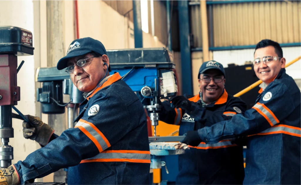 Equipo de técnicos MCAT trabajando en taller de manufactura con maquinaria industrial