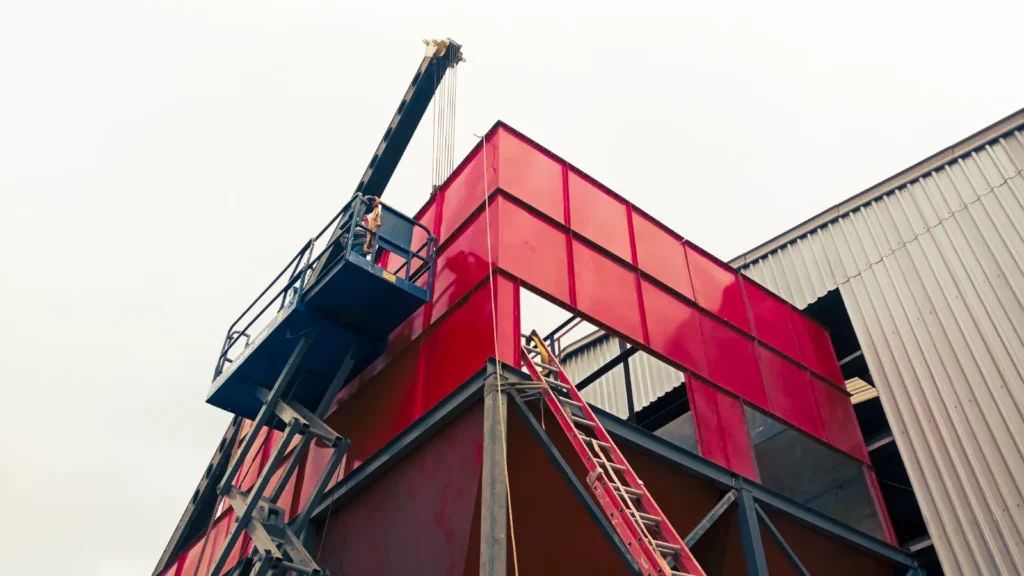 Instalación de colector de polvo industrial en planta con estructura metálica roja – MCAT.
